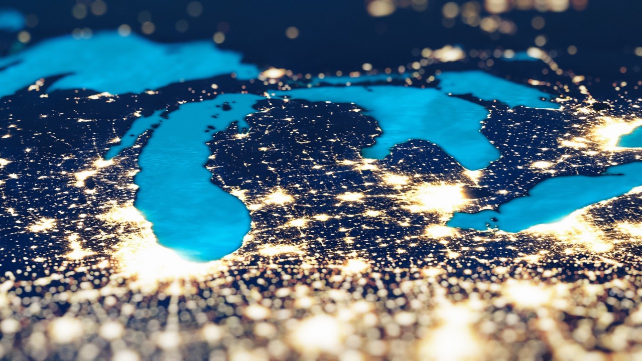 "Satellite-style image of the Great Lakes region at night, with the lakes highlighted in bright blue and surrounding cities glowing with golden lights.